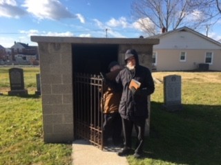 A small stone ohel with a gate, at a cemetery, in winter
